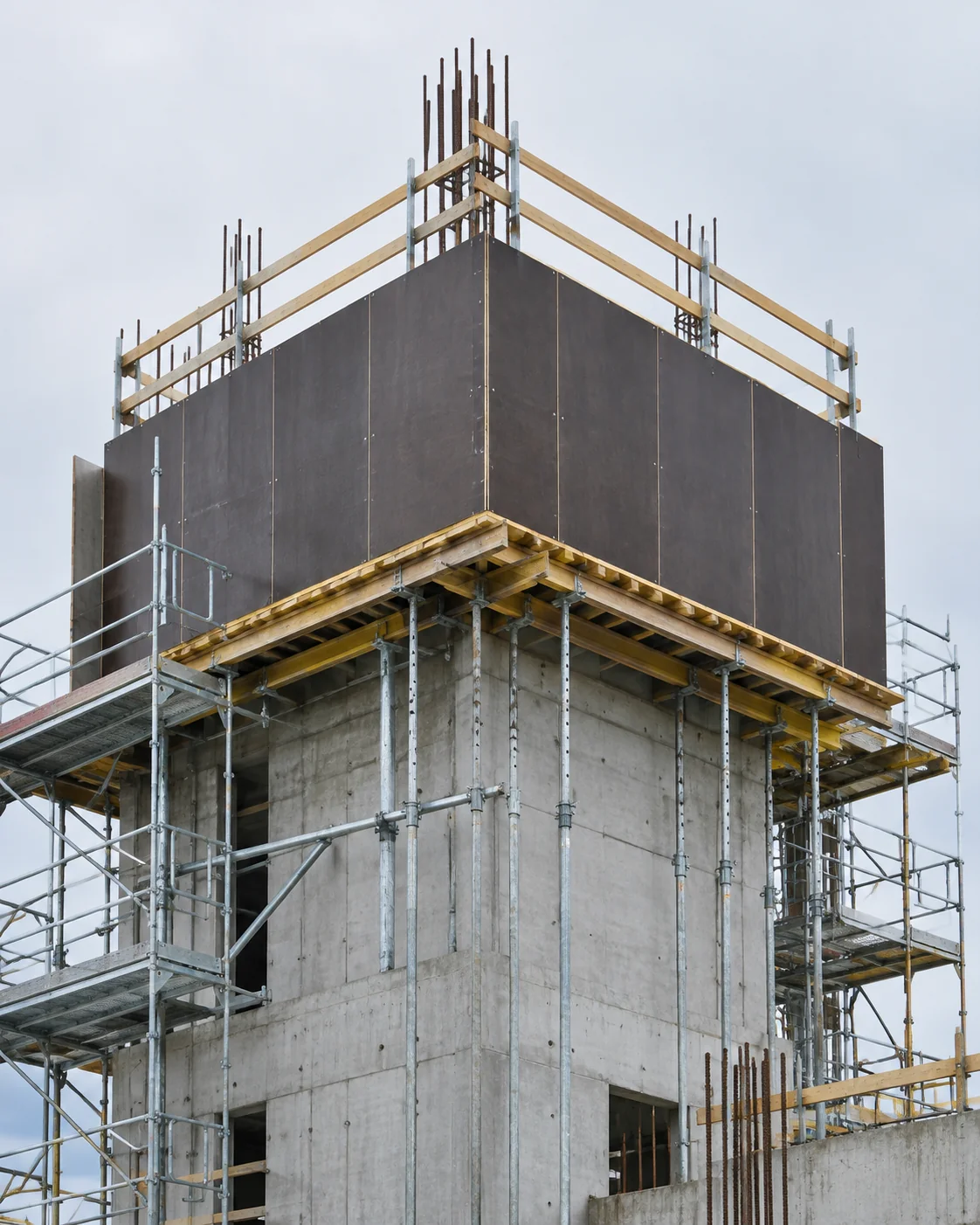 Concrete building core under construction with climbing formwork faced with dark film-faced plywood