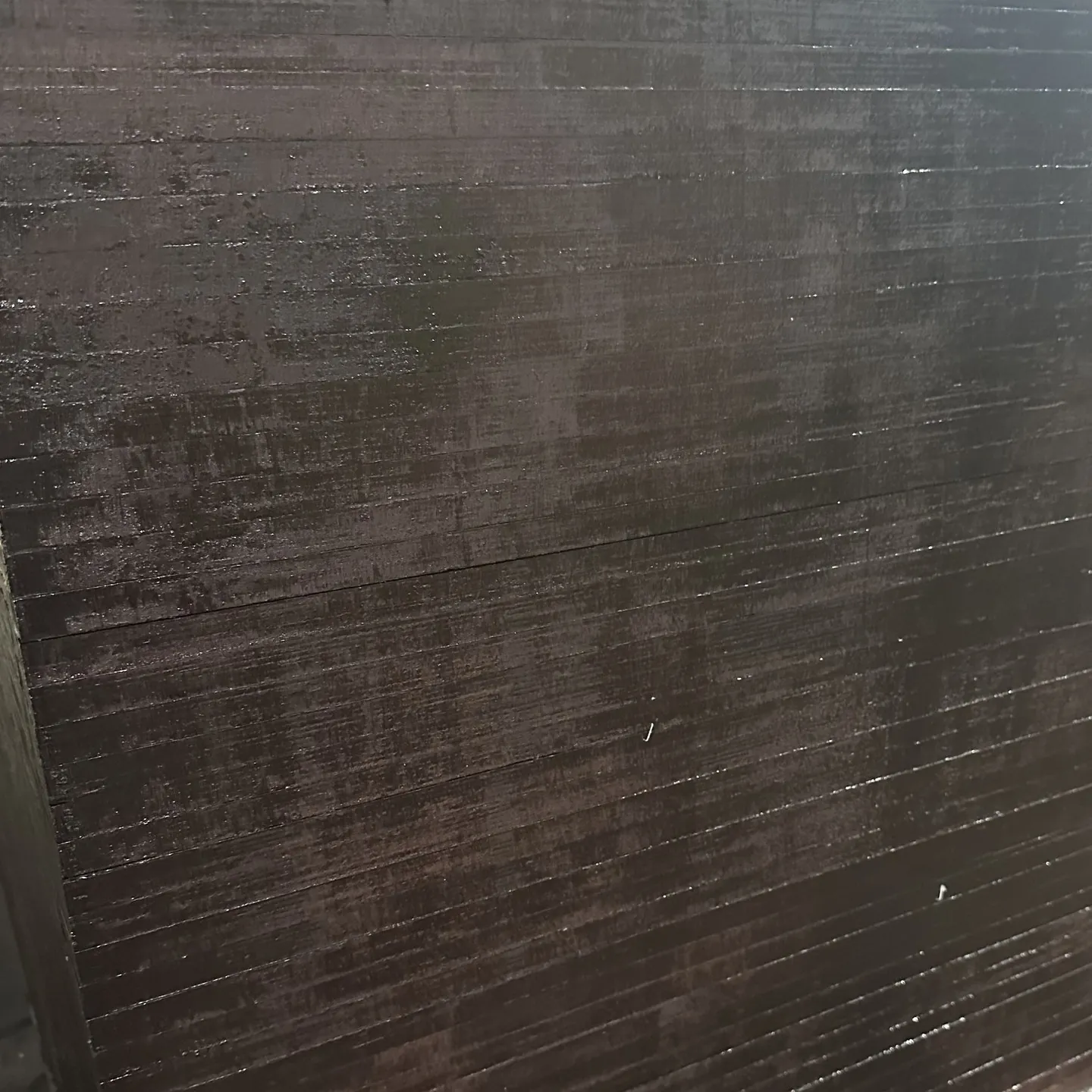 Side of a plywood pack with dark brown sealed panel edges in fine horizontal lines